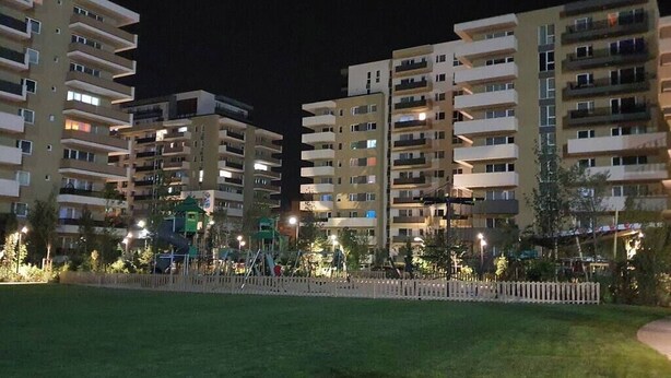 A residential building complex at night with multiple balconies and a playground area.
