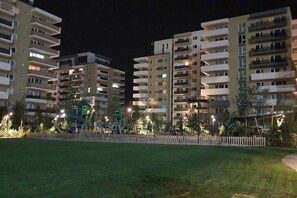 Un ensemble d’immeubles résidentiels la nuit, avec de nombreux balcons et un espace de jeux pour enfants.