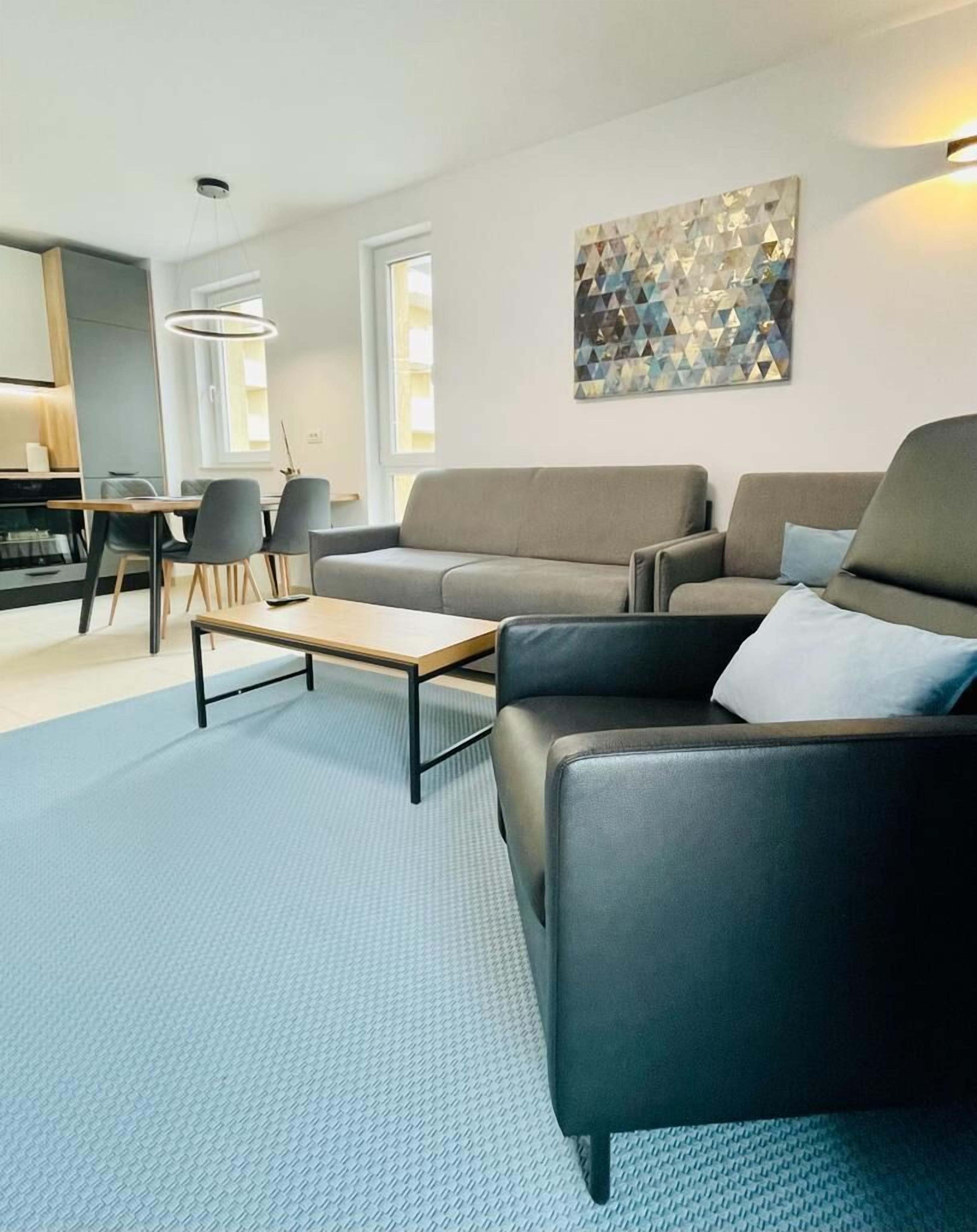 Una sala de estar moderna con un sofá, una mesa de centro y un comedor con sillas.