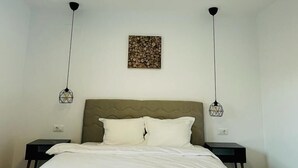 A hotel room with a bed, two bedside tables, a headboard, a wall-mounted artwork, and a ceiling light.