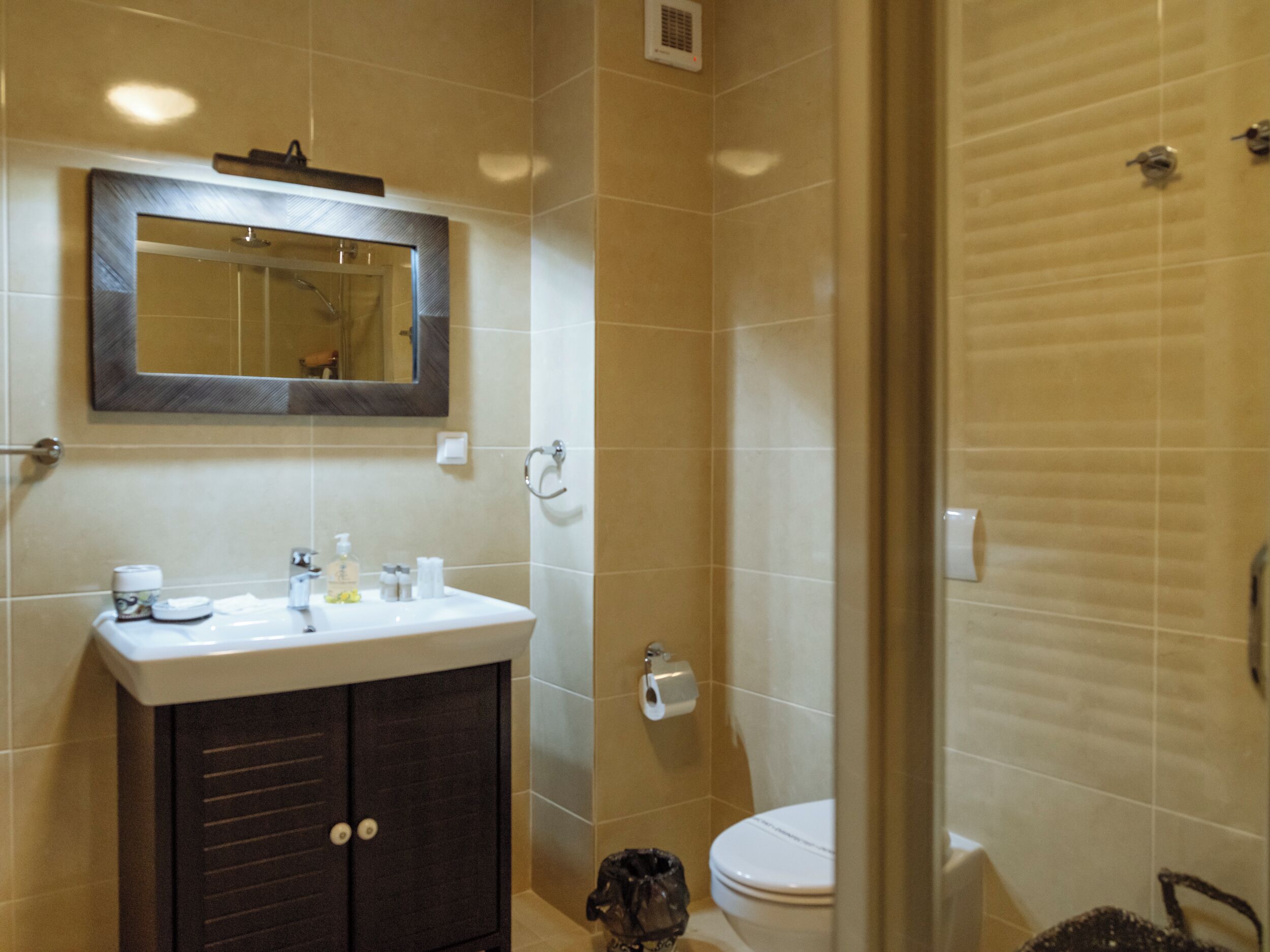 A bathroom with a sink, mirror, toilet, and shower.