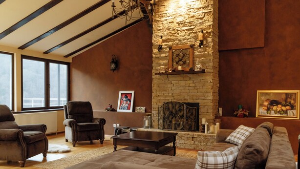 Una sala de estar acogedora con chimenea de piedra, sillones de cuero y un sofá grande.