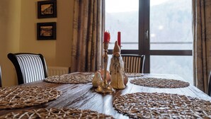 Una mesa de comedor con individuales tejidos, una figurita de gnomo y velas rojas.