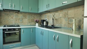 A kitchen with teal cabinets, a white countertop, and a patterned backsplash. - Cozy Flowers Studio • Near Coresi Mall (Brașov)