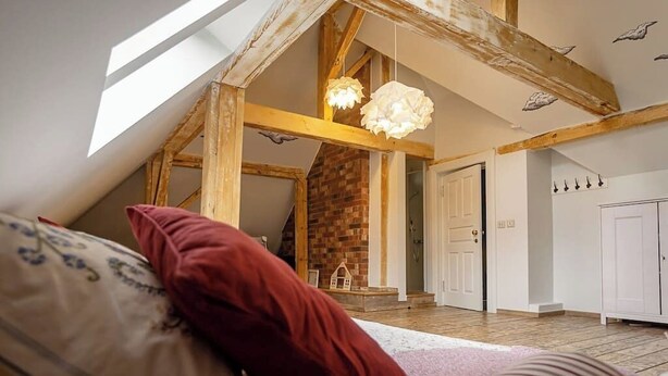 Ein Schlafzimmer im Loft-Stil mit freiliegenden Holzbalken, einem Kamin aus Backsteinen und einem Oberlicht.