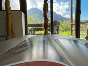 Une pièce dotée d’une grande fenêtre, d’une table en bois et offrant une vue sur les montagnes.