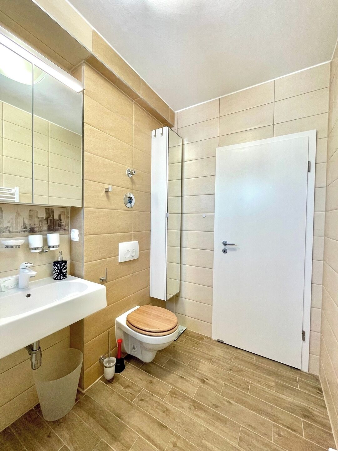 Casa de banho com lavatório, espelho, sanita e porta.