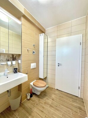 Un baño con lavamanos, espejo, inodoro y una puerta.