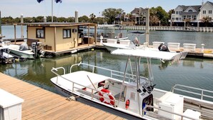 A marina with docked boats, a small building labeled "BOAT REVELS FISHING CHARTERS," and residential houses in the background.