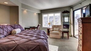 A hotel room with a large bed, a chair, a desk, and a dresser.