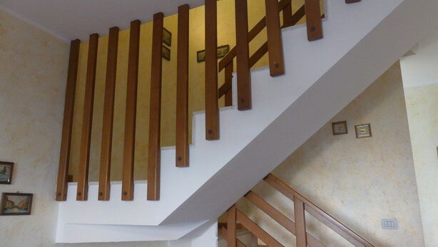 Eine Treppe mit hölzernen Handläufen und einer weißen Wand mit einigen gerahmten Bildern.