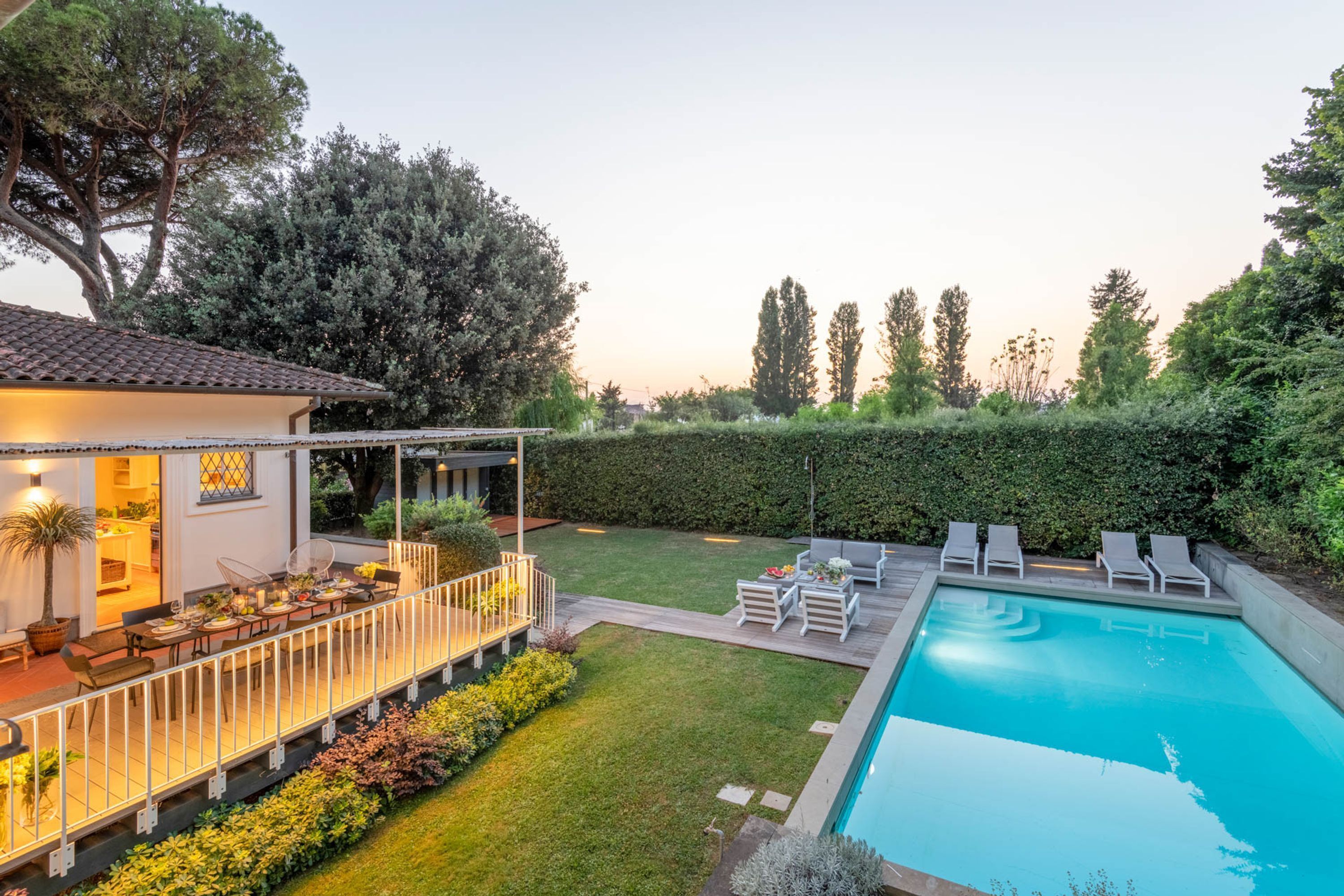 Ein Garten mit Swimmingpool, Sitzgelegenheit im Freien und einer überdachten Terrasse.