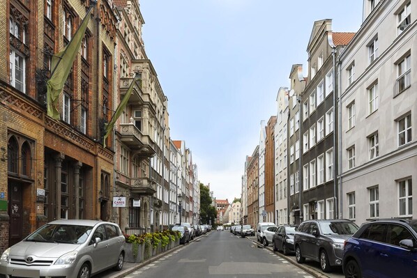 A street lined with historic buildings, parked cars, and a clear sky.