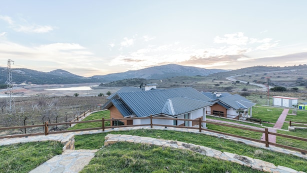 A modern house with a metal roof, surrounded by a stone pathway and wooden fence, overlooking a valley and distant mountains. - Tolstoy’un Bisikleti Gökçeada (Gökçeada)