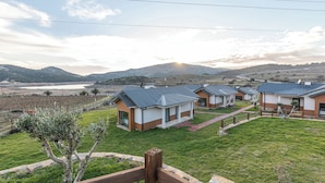 A row of modern, single-story houses with a flat roof, surrounded by a well-maintained lawn and a few olive trees. - Tolstoy’un Bisikleti Gökçeada (Gökçeada)