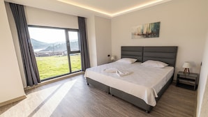 A modern hotel room with a large bed, a view of the outdoors, and a painting on the wall. - Tolstoy’un Bisikleti Gökçeada (Gökçeada)