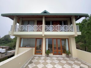 A two-story building with a balcony, large windows, and potted plants. - Sumer hotel (Pachhad)