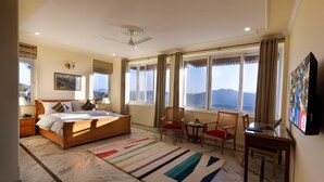 Ein geräumiges Schlafzimmer mit einem großen Bett, einem Deckenventilator und Bergblick durch die Fenster.