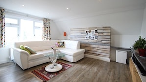 Un soggiorno moderno con un divano bianco, un tavolino in vetro e una parete decorativa in legno.