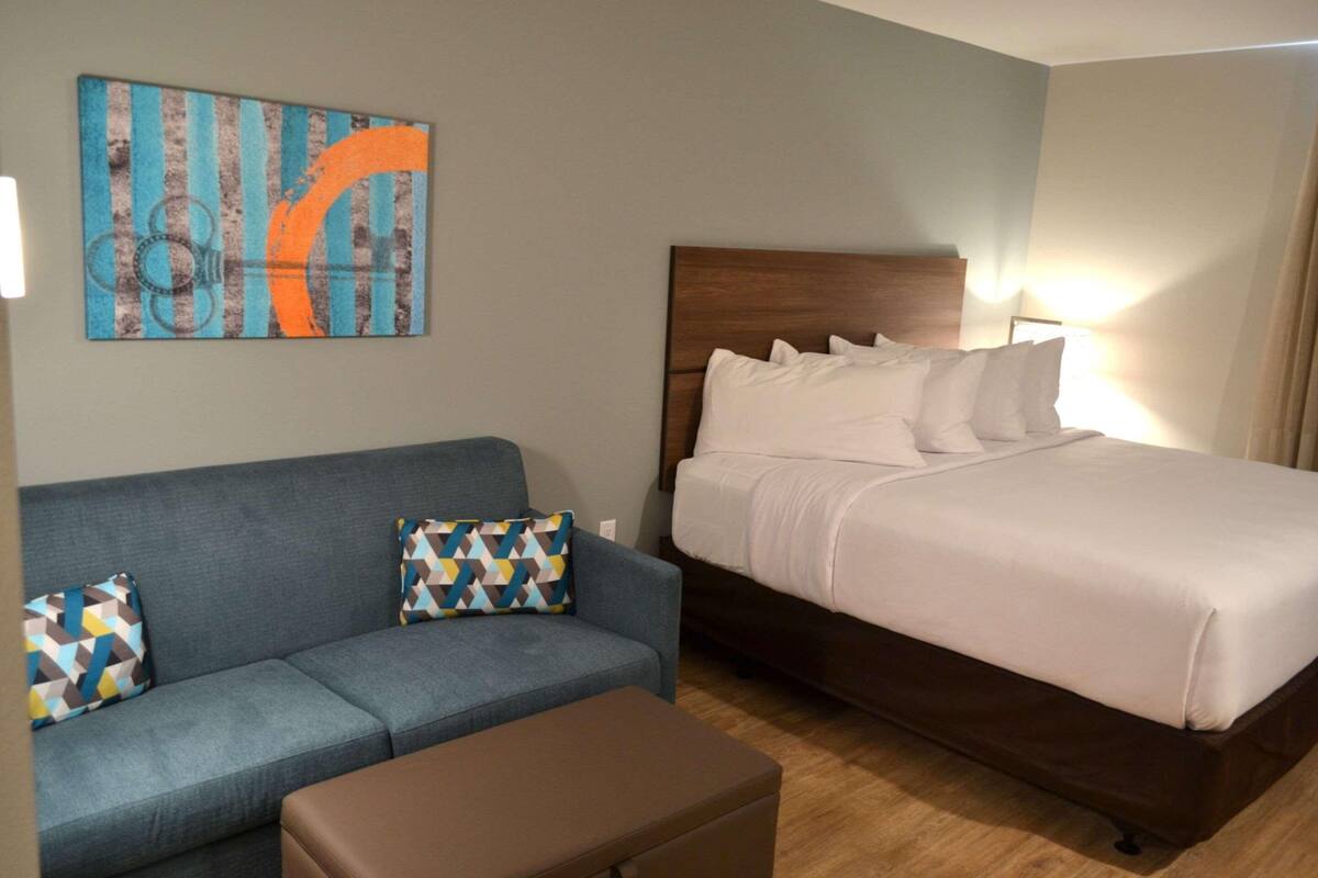 A hotel room with a bed, a sofa, and a small table.