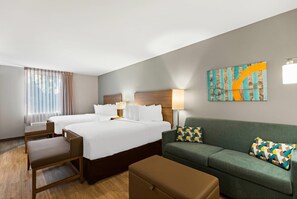 A hotel room with two beds, a sofa, a chair, a table, and a painting on the wall. - Mainstay Suites Gatlinburg TN (Gatlinburg)