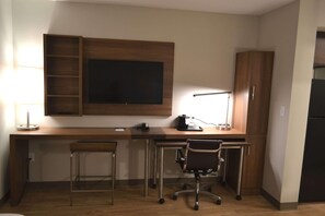 A compact office space with a desk, two chairs, a small stool, a coffee maker, and a lamp. - Mainstay Suites Gatlinburg TN (Gatlinburg)