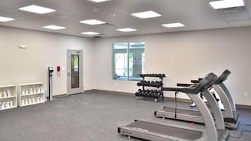 A fitness room with treadmills, dumbbells, and a water dispenser.
