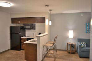 A compact kitchen with a refrigerator, microwave, and a small dining area with two chairs. - Mainstay Suites Gatlinburg TN (Gatlinburg)