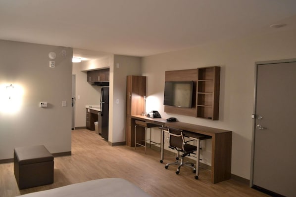A hotel room with a bed, a desk with a chair, a TV mounted on the wall, and a wardrobe. - Mainstay Suites Gatlinburg TN (Gatlinburg)