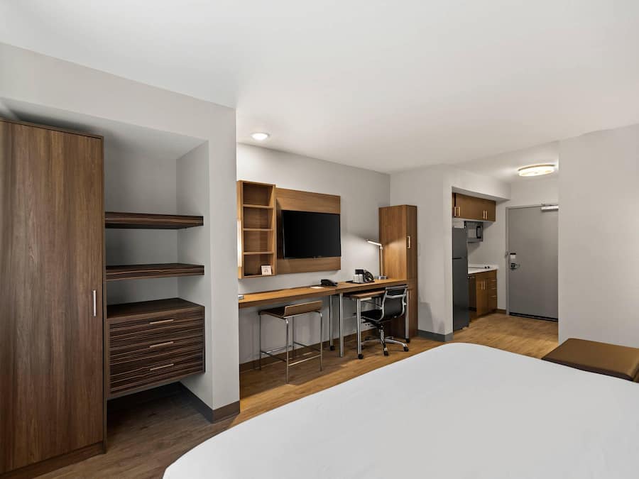 Een moderne hotelkamer met een groot bed, een bureau met stoel, een televisie en een kledingkast.