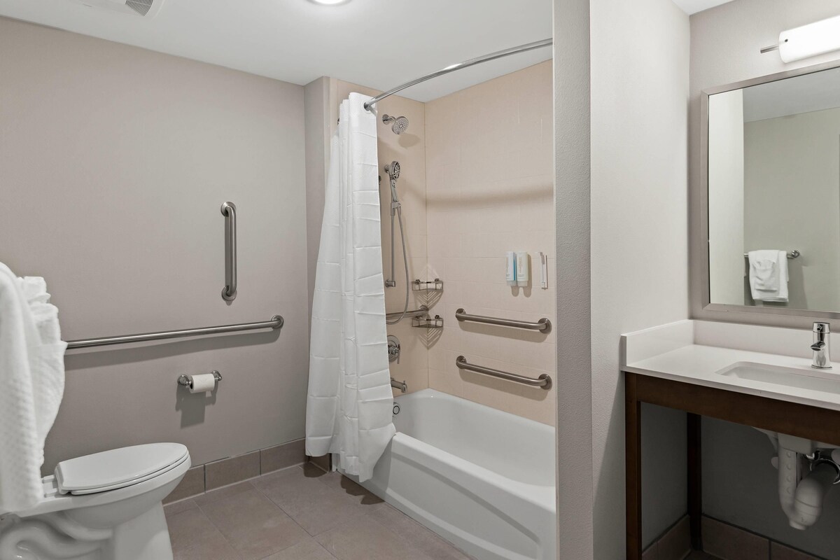 A bathroom with a toilet, shower, and sink.