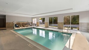 An indoor swimming pool with clear water, a lifeguard chair, and a pool ladder.
