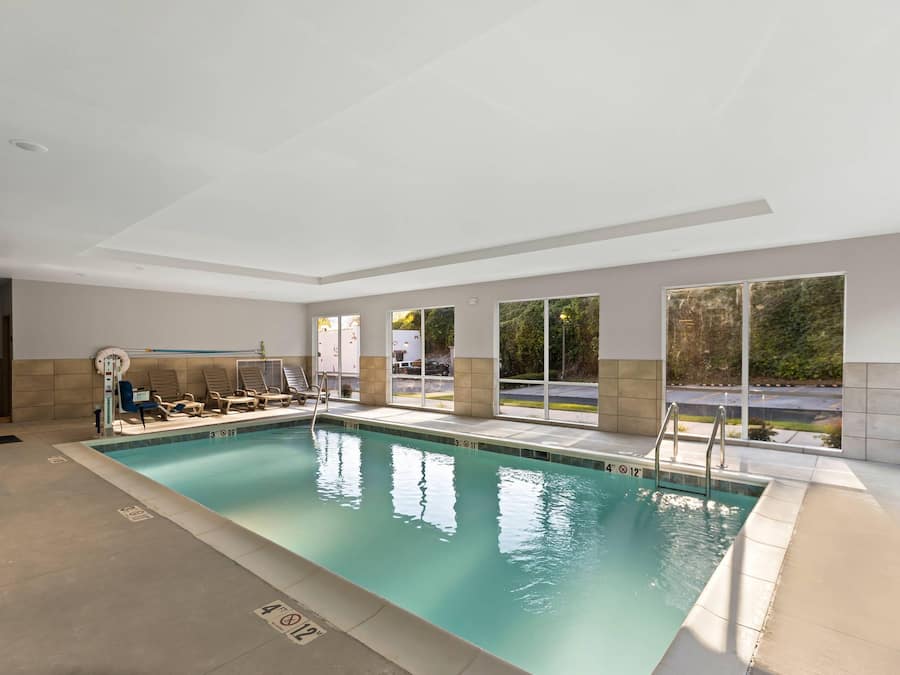 En indendørs swimmingpool med krystalklart vand, en redningsbås og en badestige.