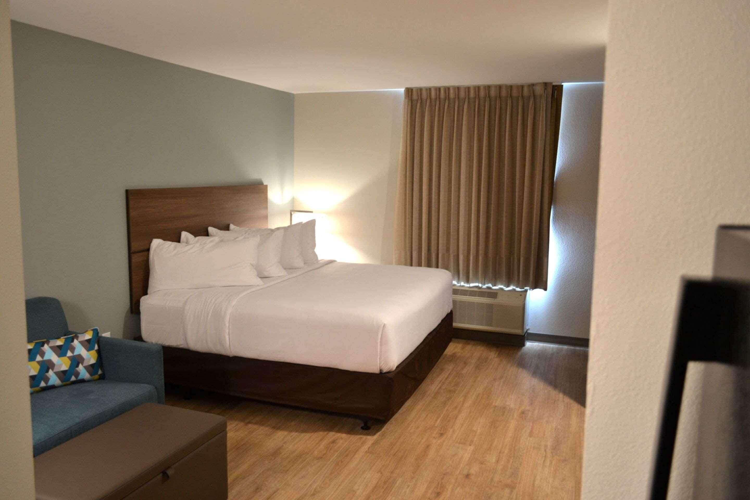A hotel room with a bed, a desk, and a chair.