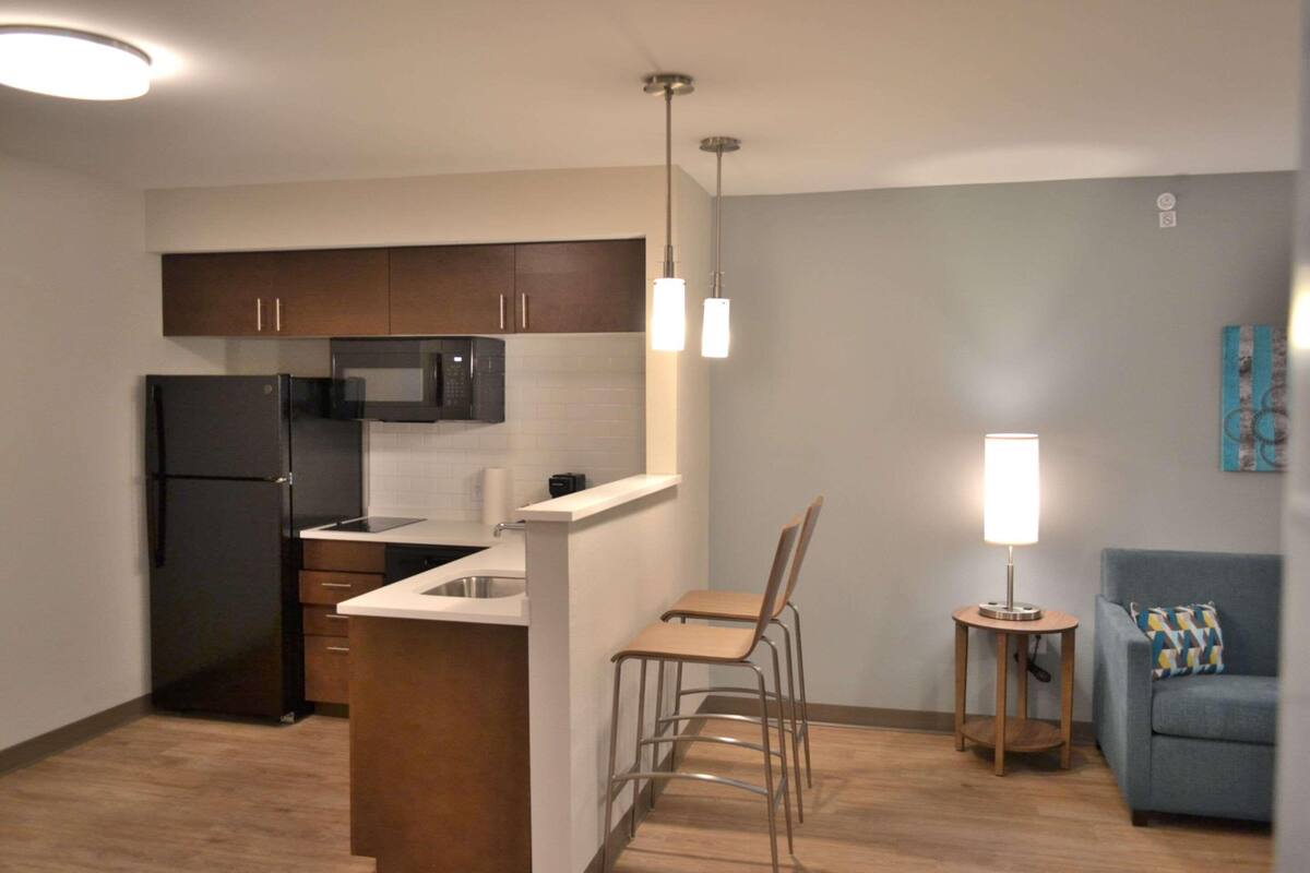 A compact kitchen with a refrigerator, microwave, and a small dining area with two chairs.