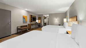 A hotel room with two beds, a desk, a chair, a bench, a TV, and a lamp. - Mainstay Suites Gatlinburg TN (Gatlinburg)