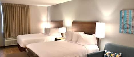 A hotel room with two beds, a sofa, and a wall-mounted artwork.