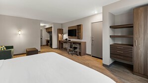 A hotel room with a large bed, a desk with a chair, a television, and built-in wardrobes.