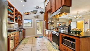 A kitchen with wooden cabinets, a built-in oven, and a microwave. - Welcome to Sunset Sails & Wagging Tails! (St. George Island)