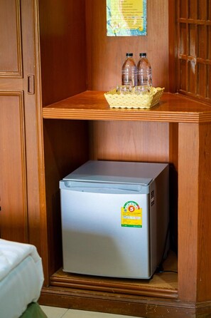 Un petit réfrigérateur orné d’un autocollant, une étagère en bois avec deux bouteilles et une carte accrochée au mur.
