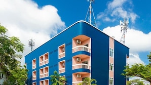 Un immeuble à plusieurs étages doté de balcons, d’une antenne parabolique et d’un petit espace couvert à l’avant.