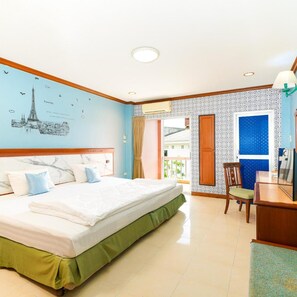 A hotel room with a large bed, a desk, and a chair. There is a window with curtains and a view of the outside. - Mayfa Hotel (Phuket)