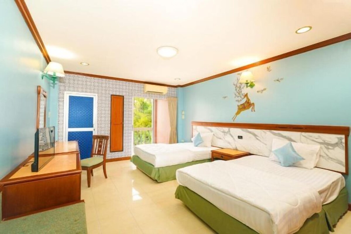 Een hotelkamer met twee bedden, een bureau, een stoel en een raam.