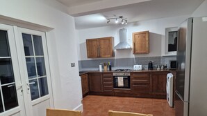 Cocina compacta con armarios de madera, estufa a gas, microondas y refrigerador.