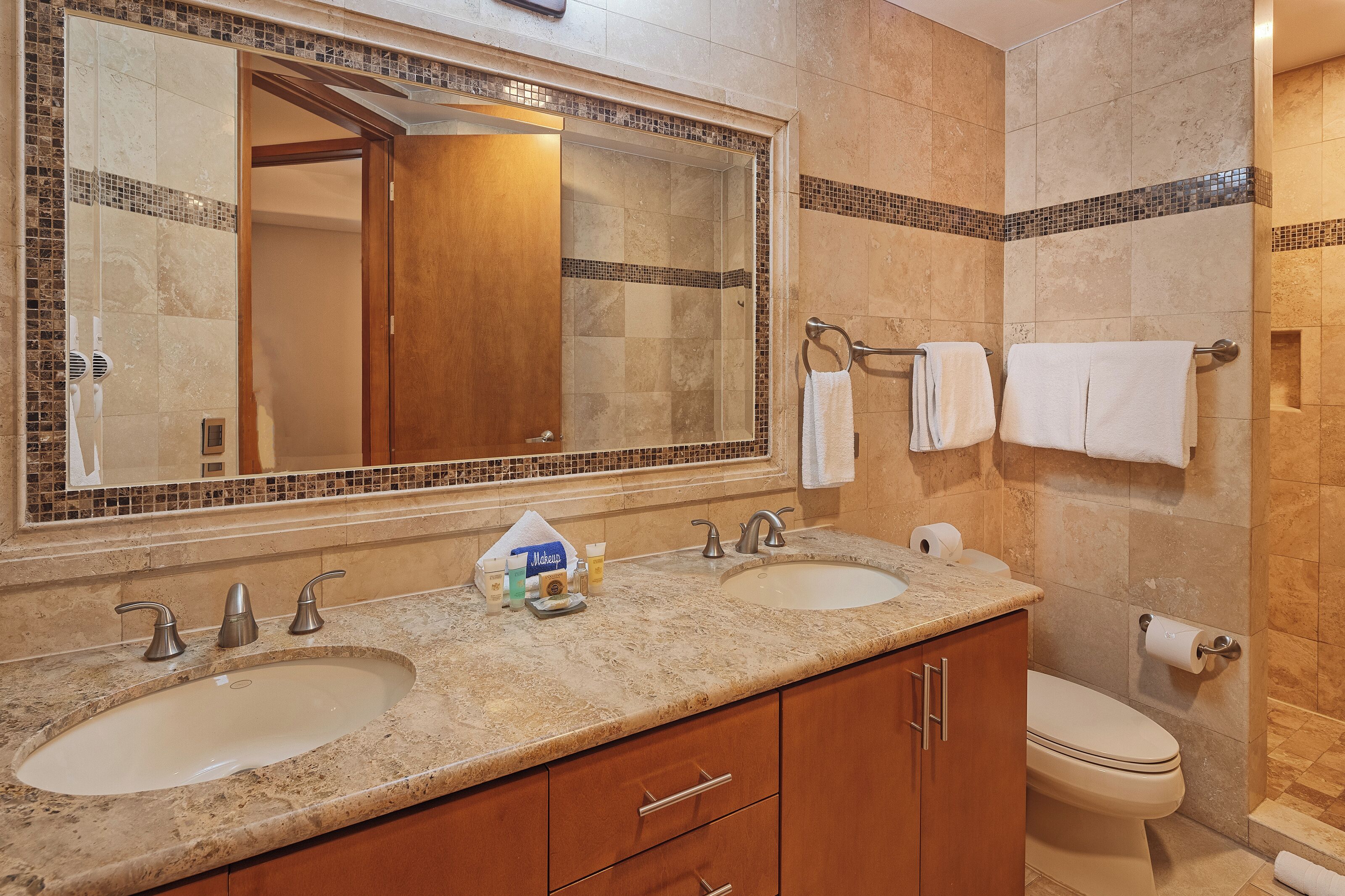 A bathroom with two sinks, a large mirror, and a shower.