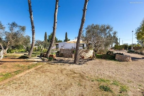 Il s’agit d’une propriété dotée d’un mur en pierre, d’un bâtiment blanc et d’un jardin agrémenté d’arbres et d’arbustes.
