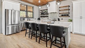 Una cocina moderna con armarios blancos, electrodomésticos de acero inoxidable y una isla central con taburetes de bar.