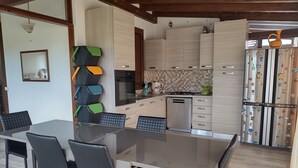 Eine moderne Küche mit Essbereich, ausgestattet mit einem großen Tisch, Stühlen und einem eingebauten Backofen.