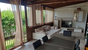 Ein modernes Wohnzimmer mit Sofa, Fernseher und Essbereich.