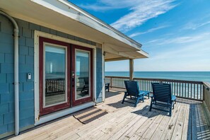 A wooden deck with a glass door leading to a balcony overlooking the ocean. - 3 BR Oceanfront | Large Deck, Seating, & Gas Grill! (Ponte Vedra Beach)